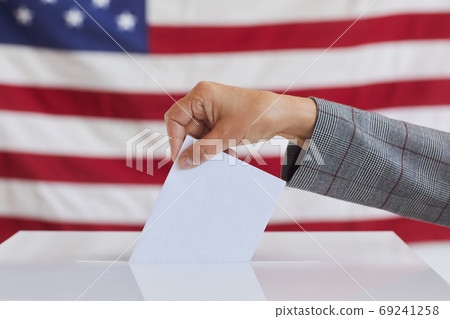 Female Hand Putting Vote in Ballot Box 69241258