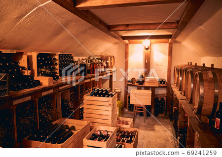 Storage room with wine in bottles and barrels. 69241259