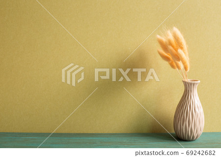 Vase of pink hares tail grass (Lagurus ovatus) dry flowers on wooden table with khaki background 69242682