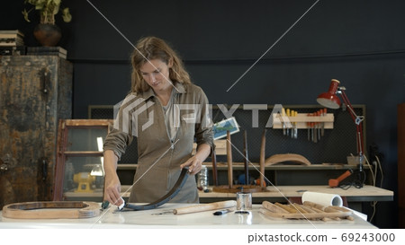 Woman painting a wooden chair leg in a workshop, restoration process Woman painting a wooden chair leg in a workshop, restoration process 69243000