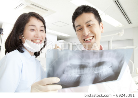 Dentist explaining to patient by X-ray 69243391