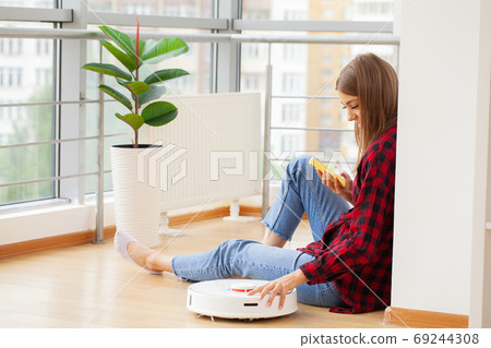 Woman turns on smart robot vacuum cleaner Woman turns on smart robot vacuum cleaner 69244308