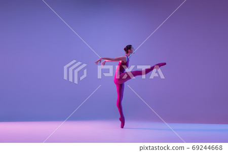 Young and graceful ballet dancer isolated on purple studio background in neon light Young and graceful ballet dancer isolated on purple studio background in neon light 69244668