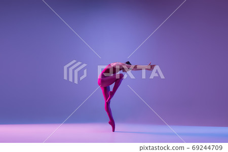 Young and graceful ballet dancer isolated on purple studio background in neon light Young and graceful ballet dancer isolated on purple studio background in neon light 69244709