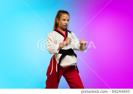 Karate, taekwondo girl with black belt isolated on gradient background in neon light Karate, taekwondo girl with black belt isolated on gradient background in neon light 69244893