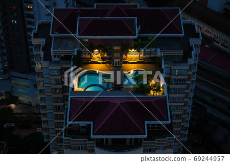 Night top view of a multi-storey residential complex with a rooftop pool Night top view of a multi-storey residential complex with a rooftop pool 69244957