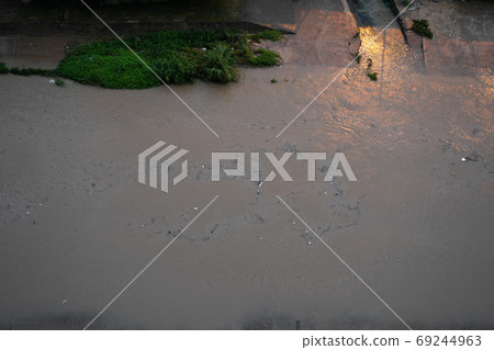 River canal in a big city. Sewage after rain carries garbage along the river. 69244963
