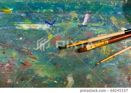 Brushes on an easel stained with paints in the artist's studio 69245337