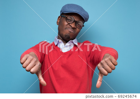 African man giving thumbs down gesture, looking with negative facial expression 69245674