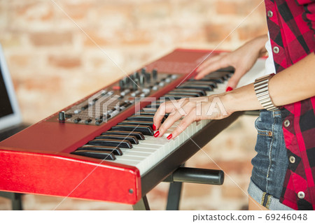 Woman recording music, singing and playing piano while standing in loft workplace or at home 69246048