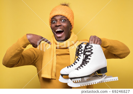 African young man in yellow hat and scarf with winter skates 69246827