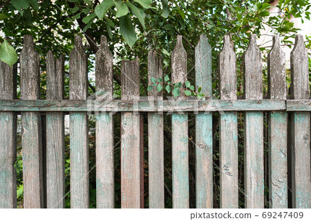 Old weathered green and grey wooden fence made of planks 69247409