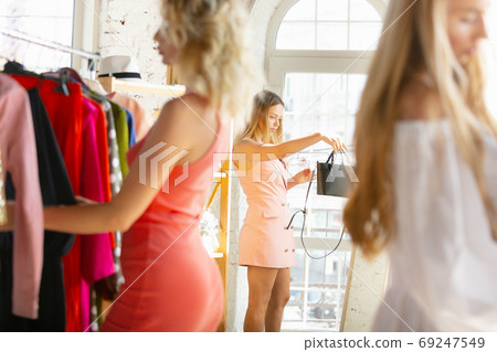 Wear, clothing shop during sales, summer or autumn collection. Young women looking for new attire Wear, clothing shop during sales, summer or autumn collection. Young women looking for new attire 69247549
