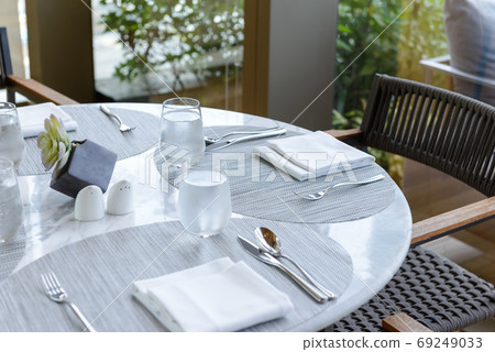 Tableware setting in the restaurant. Decorated elegant table, glasses, napkin, knife, fork and spoon 69249033