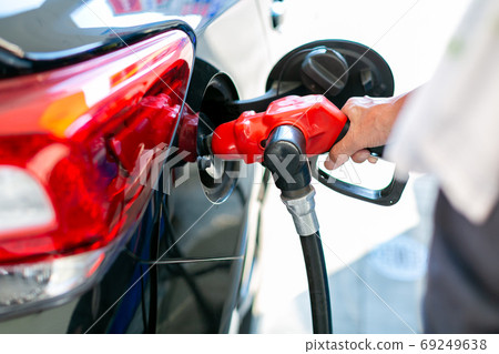 A man who refuels at a gas station 69249638