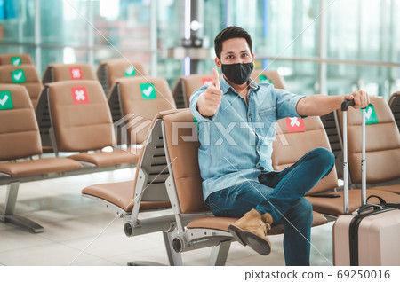 Asian man wearing mask sitting on social distancing chair showin 69250016