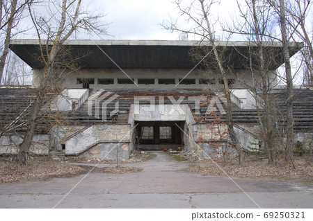 An abandoned football stadium in Pripyat. Overgrown with trees ruins of the stadium. 69250321