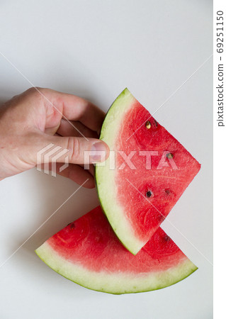 Male hahd holding slice of ripe watermelon on white background, top view Male hahd holding slice of ripe watermelon on white background, top view 69251150