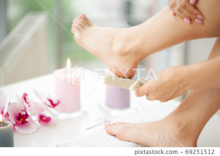 Woman cleans the heel of the foot with pumice Woman cleans the heel of the foot with pumice 69251512