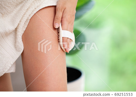 Cellulite treatment, woman arm holding dry brush to top of her leg. Cellulite treatment, woman arm holding dry brush to top of her leg. 69251553