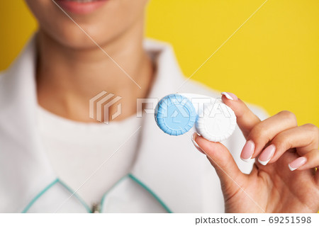 Close up of woman holding container with contact lenses 69251598