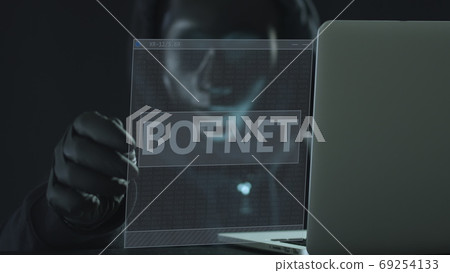 A hacker wearing black pulls BOTNET tab from a laptop. Hacking concept 69254133