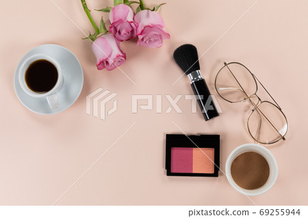 Make up view with pink flowers and cup of coffee and glasses on pink background 69255944