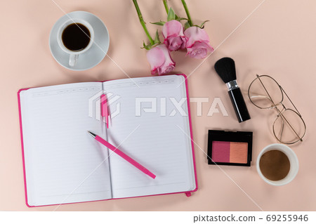 Make up view with pink flowers, notebook, cup of coffee and glasses on pink background Make up view with pink flowers, notebook, cup of coffee and glasses on pink background 69255946