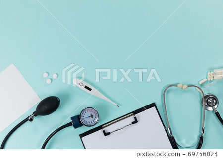 View of a composition with medical devices, pills and a folder with a sheet of paper on blue surface 69256023