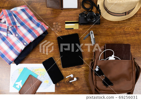 View of a variety of essential travelling items with tablet, smartphone and camera on wooden table 69256031