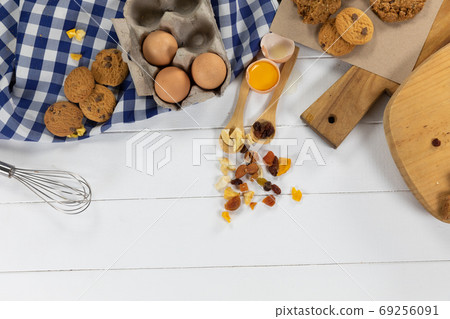 View of cookies, spoons with dried fruits and eggs on white wooden surface with tablecloth 69256091