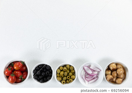 View of a six bowls with fresh tomatoes, olives, nuts and seasoning on plain white surface View of a six bowls with fresh tomatoes, olives, nuts and seasoning on plain white surface 69256094