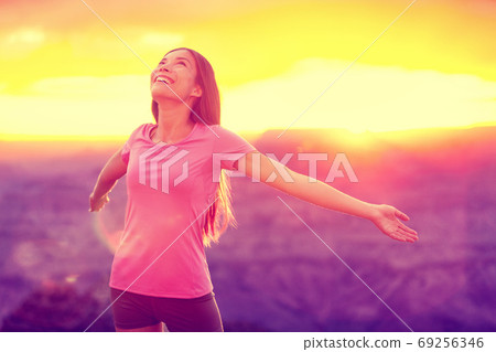 Free happy woman enjoying nature sunset. Freedom, happiness and enjoyment concept of young multiracial Asian chinese girl with open arms in hope and success with Grand Canyon mountains, USA. 69256346