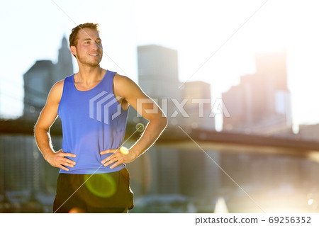 Sport athlete man running looking away at New York City - Brooklyn Bridge and Manhattan skyline copy space. Active healthy lifestyle fit fitness runner outside training fitness workout outdoor in NYC. 69256352