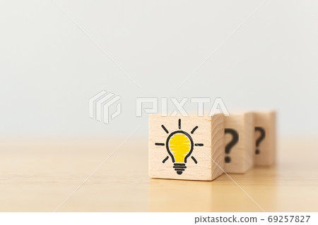 Wooden cube block with light bulb icon and question mark symbol 69257827