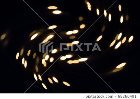 Flying golden swirling bokeh lights on black. Holiday background 69260491