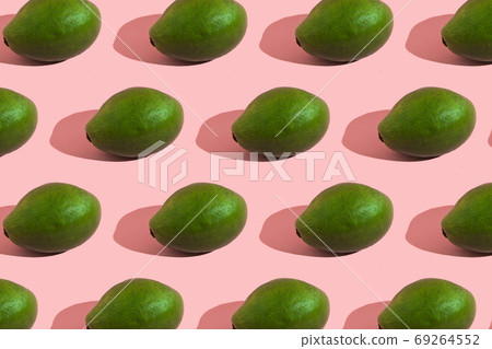 Trending style pattern of a whole green avocado on a pink background with hard light. Creative food texture. Trending style pattern of a whole green avocado on a pink background with hard light. Creative food texture. 69264552