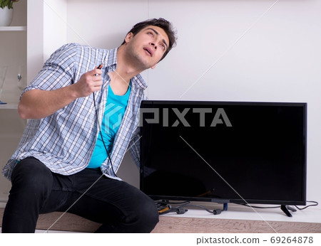 Man trying to fix broken tv Man trying to fix broken tv 69264878