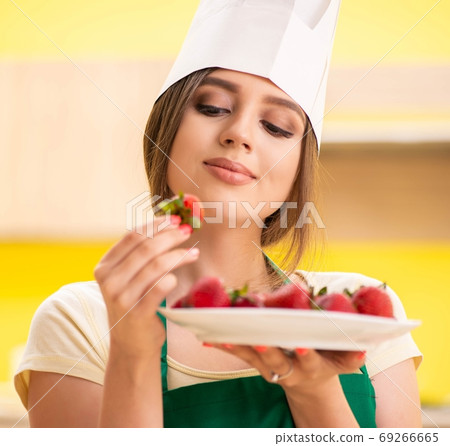 Young female cook eating strawberries 69266665