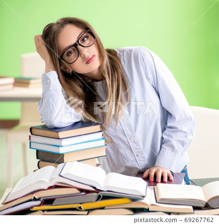 Young female student preparing for exams with many books Young female student preparing for exams with many books 69267762