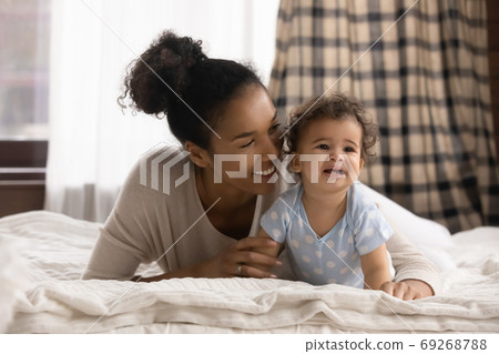 Affectionate mixed race woman lying on bed with cute baby. 69268788