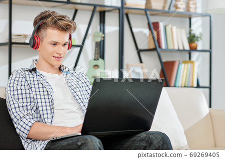 Teenage boy playing on laptop 69269405