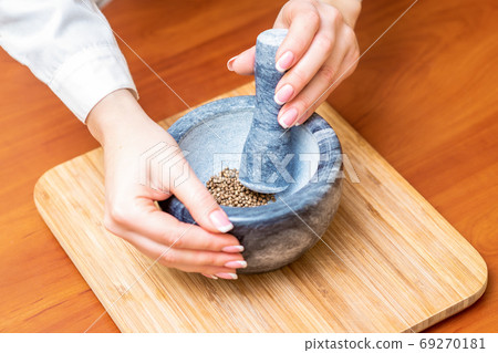 Hands of woman grinding pepper in mortar Hands of woman grinding pepper in mortar 69270181