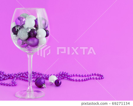 Christmas baubles in a wine glass on a purple background 69271134