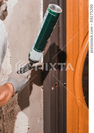 The worker foams and insulates the door, uses a carpenter's foam gun, a close-up of the work process. The worker foams and insulates the door, uses a carpenter's foam gun, a close-up of the work process. 69273200