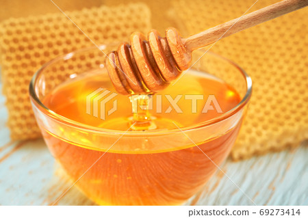 bowl sweet honey on blue rustic table, with honeycomb, close-up. bowl sweet honey on blue rustic table, with honeycomb, close-up. 69273414