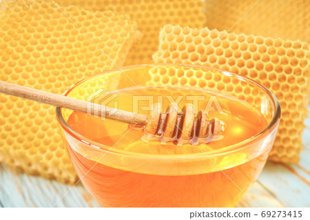 bowl sweet honey on blue rustic table, with honeycomb, close-up. bowl sweet honey on blue rustic table, with honeycomb, close-up. 69273415