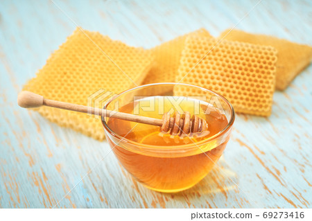 bowl sweet honey on blue rustic table, with honeycomb. bowl sweet honey on blue rustic table, with honeycomb. 69273416