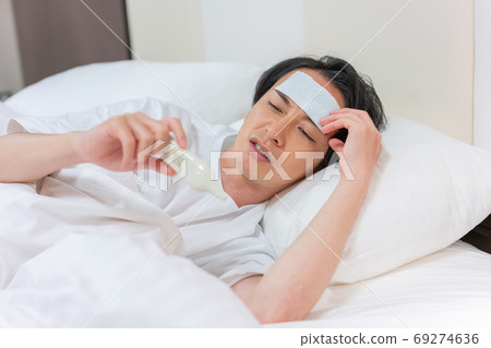 Young men measuring heat with a thermometer Young men measuring heat with a thermometer 69274636