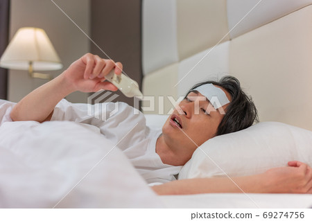 一個年輕人在晚上用溫度計測量他的熱量 一個年輕人在晚上用溫度計測量他的熱量 69274756